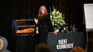 Female speaker at Letting Agent Today event with floral arrangement and presentation tools.