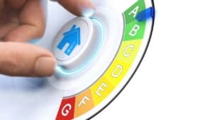 Person pressing a home energy efficiency button with a colourful rating scale.