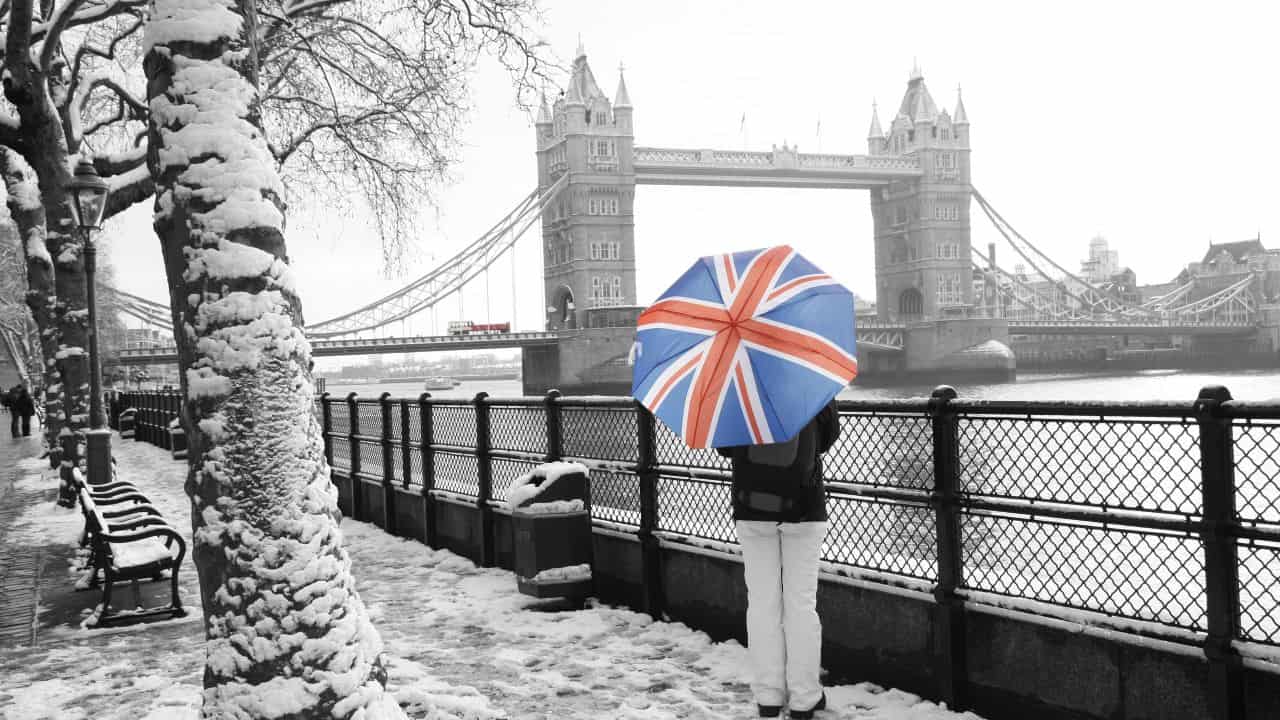 Person with Union Jack umbrella by Tower Bridge in winter.