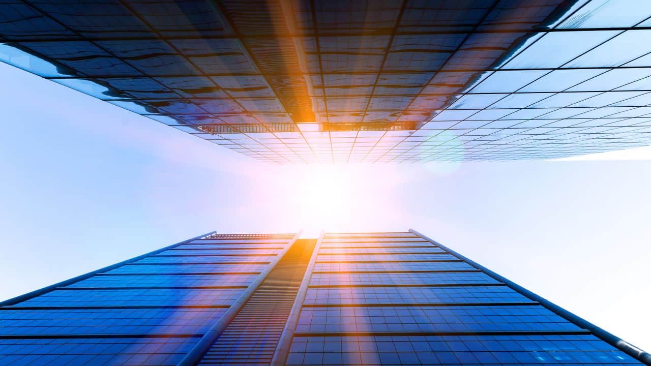 Tall modern skyscraper reflecting sunlight with a clear blue sky.