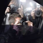 Photographers taking pictures inside a car with camera reflections on the window.