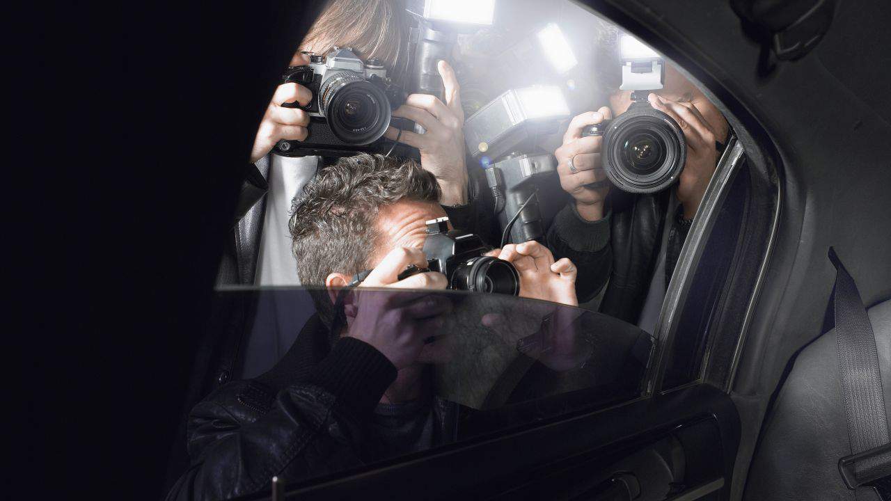 Photographers taking pictures inside a car with camera reflections on the window.