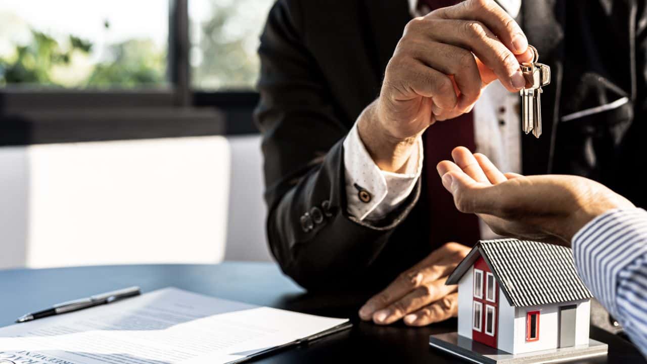 Real estate agent handing over keys to new tenant or owner.