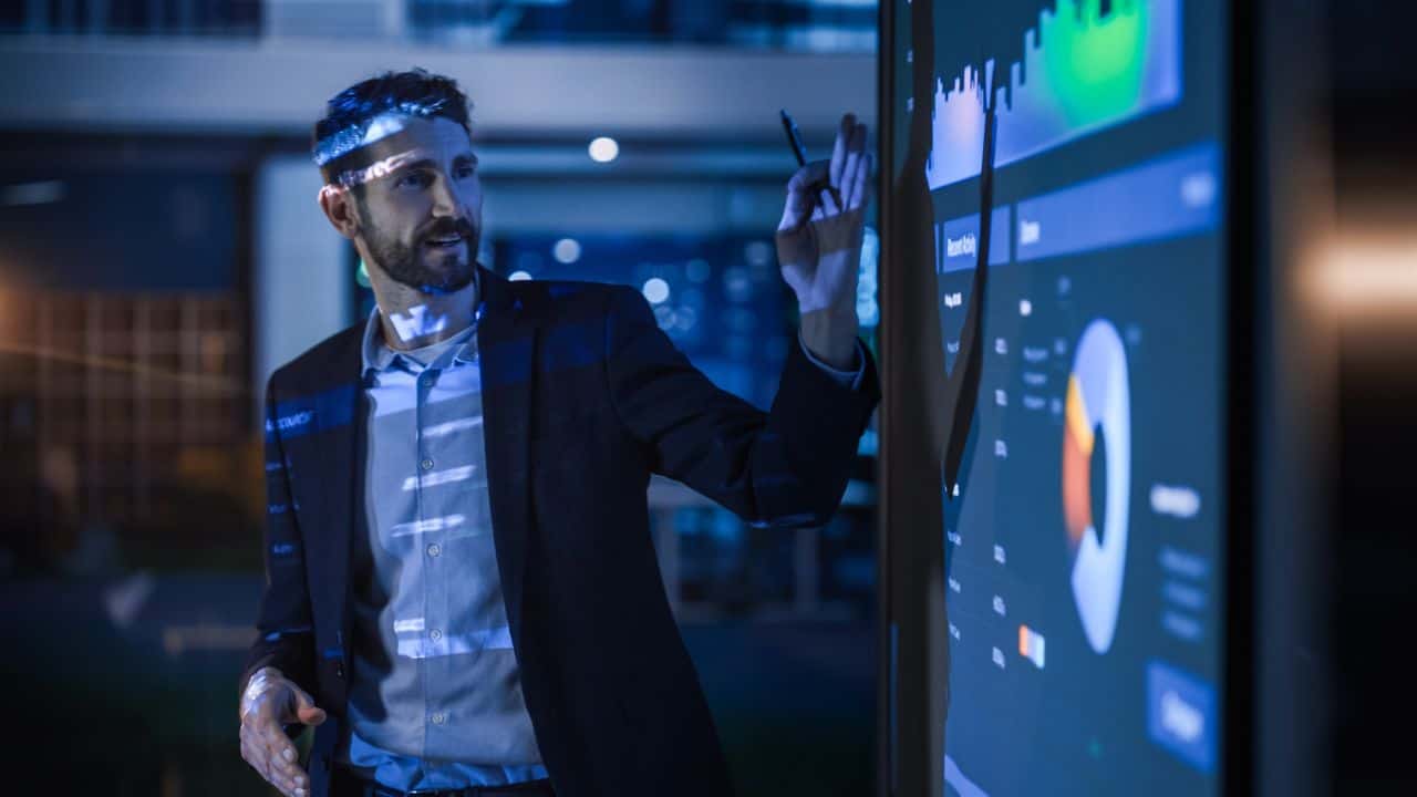 Businessman analyzing digital market data on large screen.