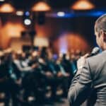 Speaker presenting at Letting Agent Today conference with audience in background.