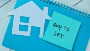 House icon and 'Buy to Let' sticky note on a desk.