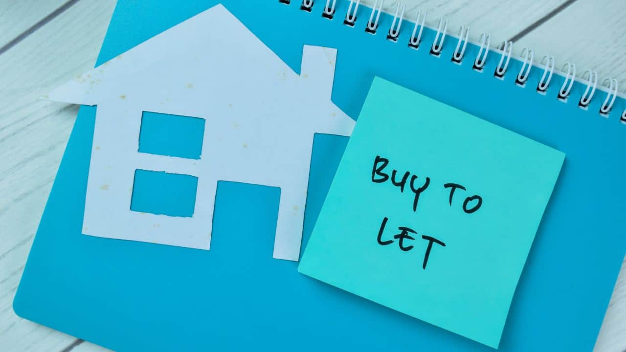 House icon and 'Buy to Let' sticky note on a desk.