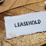 Leasehold written on torn paper with sand and shells background.