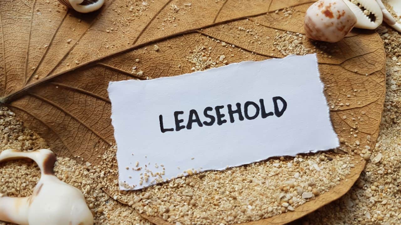 Leasehold written on torn paper with sand and shells background.