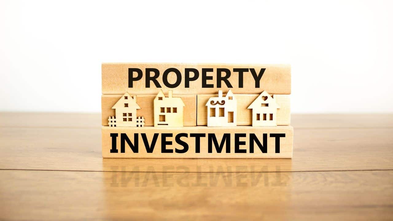Wooden blocks spelling Property Investment with small house models.