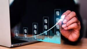 Hand drawing upward trend graph on digital screen for property market.