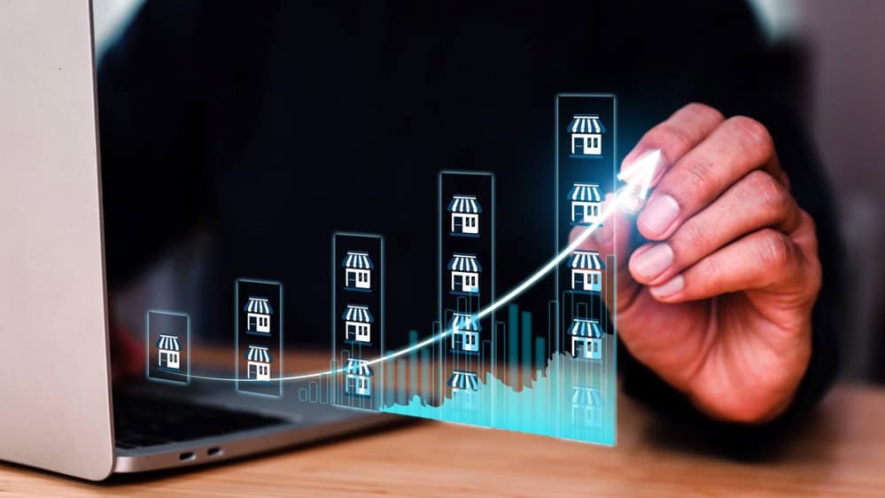 Hand drawing upward trend graph on digital screen for property market.