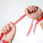 Two hands breaking a red and white striped ribbon symbolising success in letting.