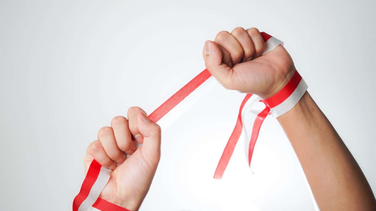 Two hands breaking a red and white striped ribbon symbolising success in letting.